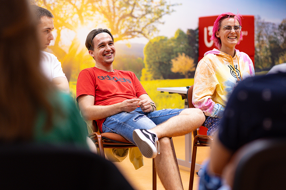 student i studentka siedzą na krzesłach i uśmiechają się